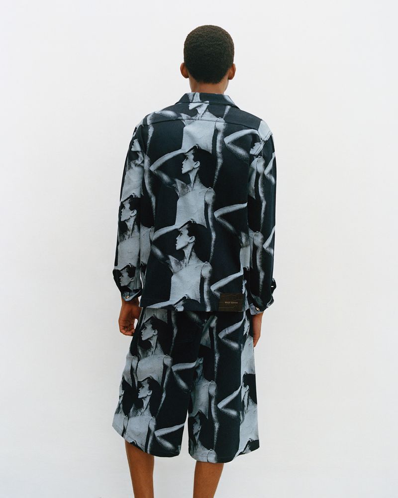 Model seen from behind wearing a patterned long-sleeve shirt and matching shorts against a white background