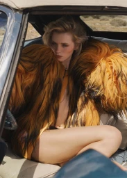 Model seated inside a vintage car wearing a voluminous orange and black textured coat for Instyle Magazine Desert Flower editorial.