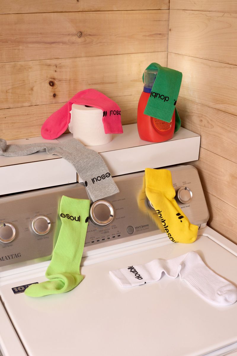 Colorful assortment of socks and laundry supplies arranged on top of a white washing machine with a wood panel background.