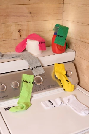 Colorful assortment of socks and laundry supplies arranged on top of a white washing machine with a wood panel background.
