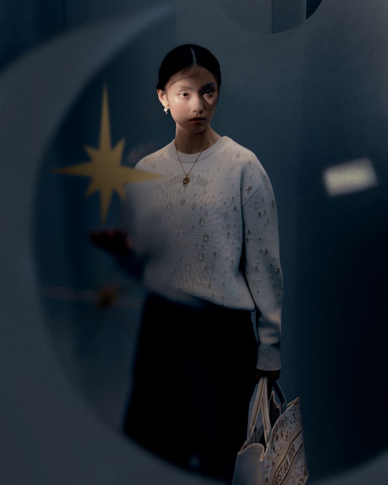 Model Tinglei Liu holding star prop, wearing Dior sweater and carrying tote bag