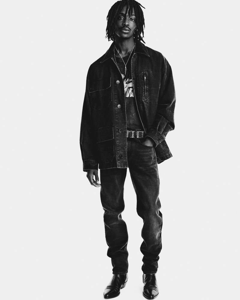 Model with dreadlocks wearing dark denim jacket and matching jeans against a white seamless background