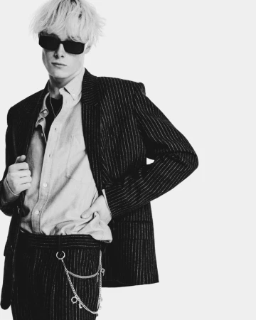 Model with blonde hair and sunglasses wearing a pinstripe suit jacket for Isabel Marant F/W 25 Men's Lookbook.