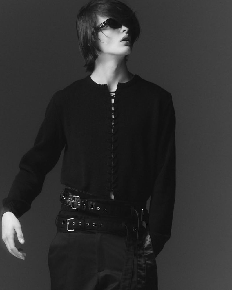 Model wearing dark sunglasses and a black laced top with layered belts for the a.v. vattev F/W 25 lookbook.