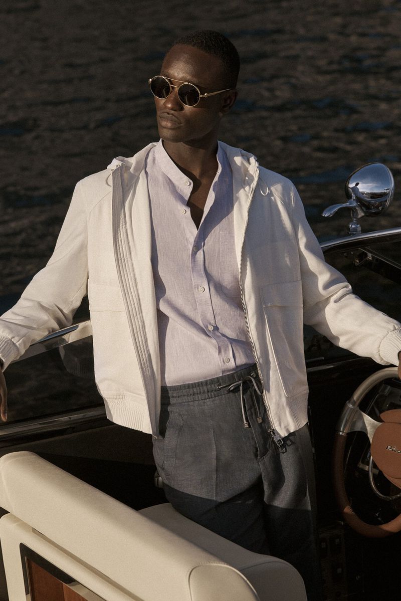 Black man in sunglasses and stylish casual outfit on a boat with water background in outdoor setting. Fashion and lifestyle shot.