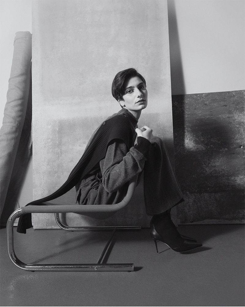 Model seated on a tubular steel chair against layered studio panels in Eudon Choi Prefall 2025 editorial