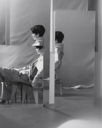 Model Nino Julakidze seated on a wooden chair reflected across multiple intersecting panels for Eudon Choi