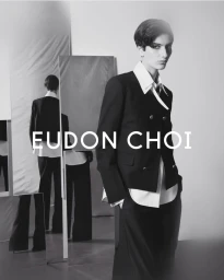 Model in black double breasted blazer and white shirt with mirrors reflecting back