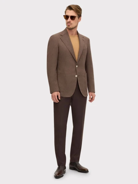 Full-length shot of an adult male model in a brown suit and sunglasses posing against a white background in a fashion style photo.