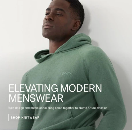 Studio shot of a Black male model wearing a hooded knit sweatshirt, showcasing modern menswear fashion against a neutral background.