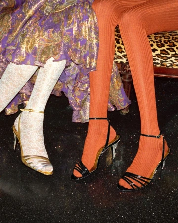 Close-up of seated models wearing patterned tights and strappy high heels for the Valentino Holiday 2024 collection.