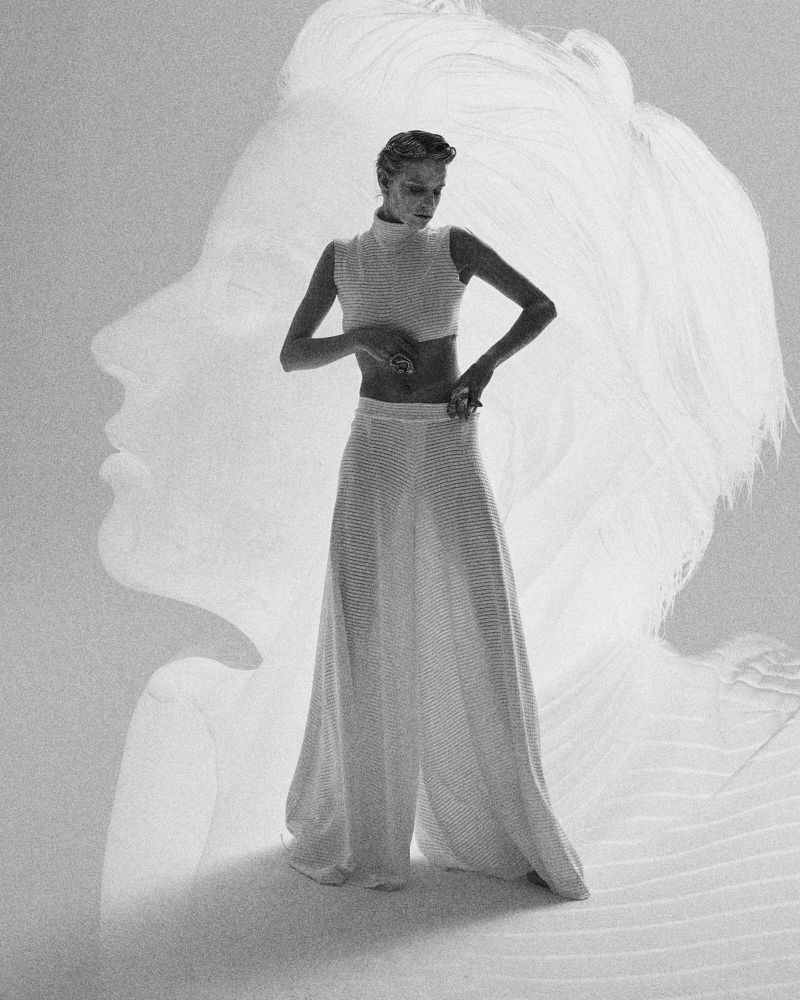 Monochromatic fashion shot of a woman posing in a knit crop top and wide-leg pants, overlaid with a semi-transparent female profile.