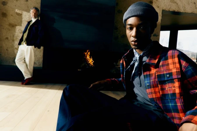 Two stylish men in casual wear. One poses indoors near a fireplace, while another leans against a stone wall, bathed in sunlight.
