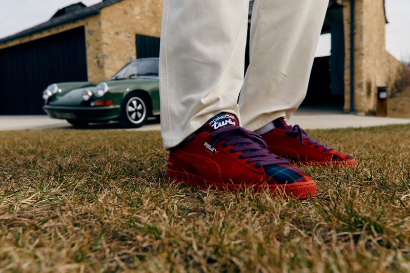 Close-up of red Puma sneakers with purple laces and a green Porsche in the background. Fashionable automotive crossover.