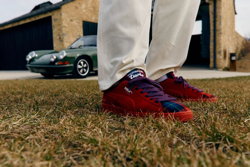 Close-up of red Puma sneakers with purple laces and a green Porsche in the background. Fashionable automotive crossover.