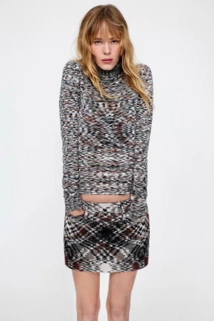 Model wearing a patterned turtleneck top and matching miniskirt against a plain white background