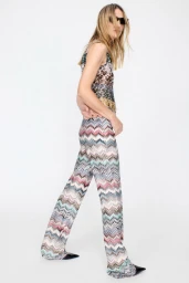 Model wearing a patterned multicolored sleeveless jumpsuit and black sunglasses against a white background