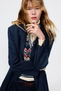 Model wearing a navy chevron patterned blazer and patterned knit top against a plain light background