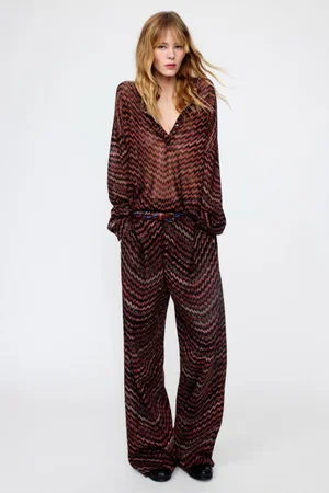 Model in patterned chevron knit top and matching wide-leg trousers against white studio background