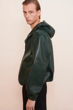 Model wearing a dark green hooded leather jacket against a light neutral background