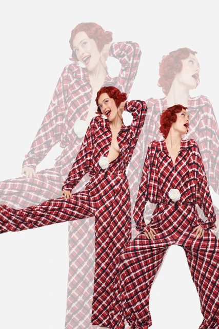 Adult female fashion model wearing plaid pajama set with flower accent poses in a studio with red hair and fair skin.