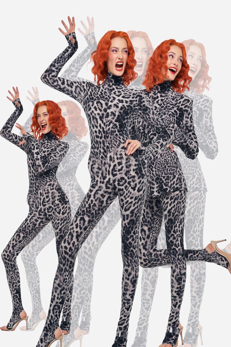 A woman with red hair poses in a grey leopard print catsuit and heels, against a bright white background, captured with dynamic, energetic poses.