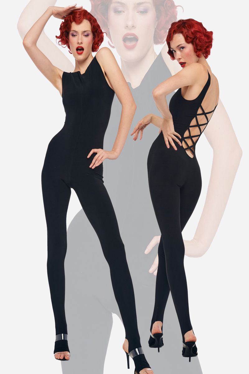 Two women pose in black bodysuits and high heels against a soft white backdrop, showcasing fashion and elegance.
