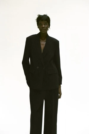Model wearing a black blazer and matching trousers against a white background for Zara A/W 25