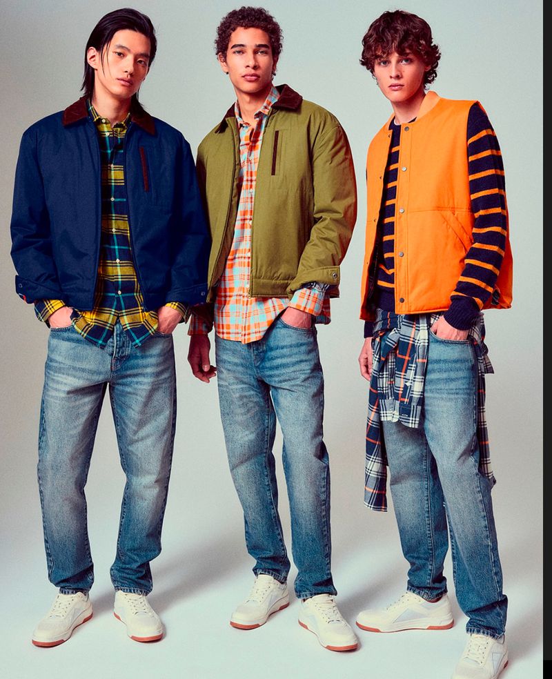 Three young adult men showcase casual fashion: jackets, plaid shirts, and jeans. The studio shot features a clean backdrop and full-body view.