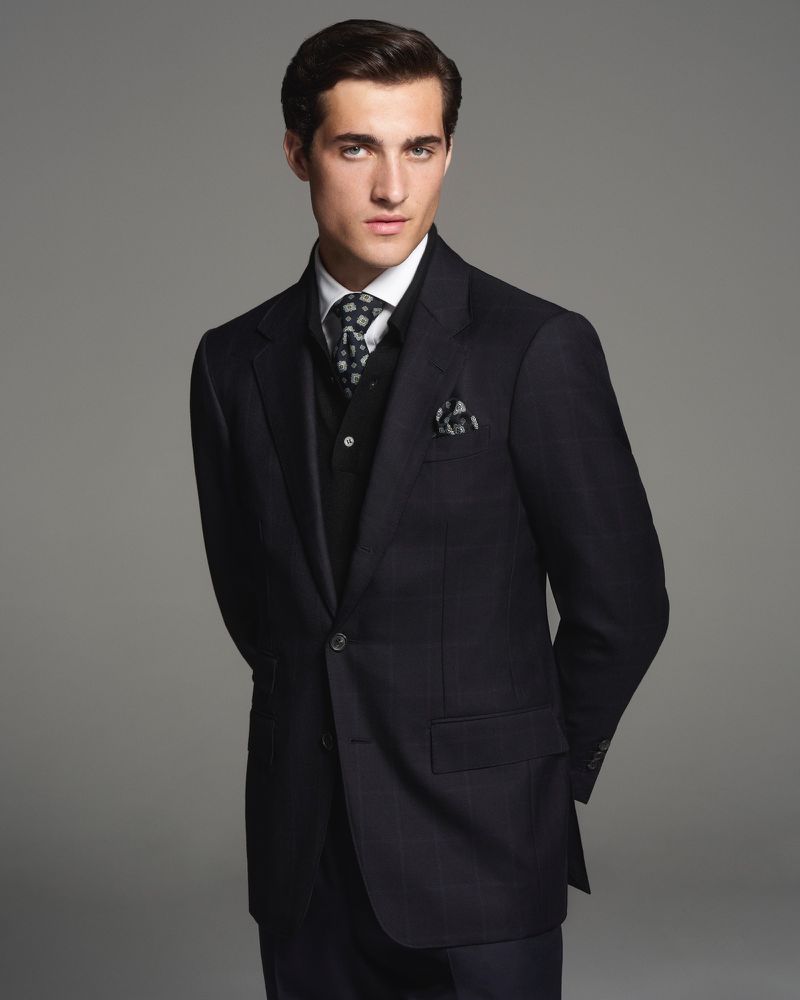 Model Adam Sattrup in a black suit with patterned tie against a grey background for Dunhill photographed by Chris Lensz