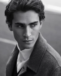 Close-up black and white portrait of a male model wearing a collared shirt and dark outerwear piece.
