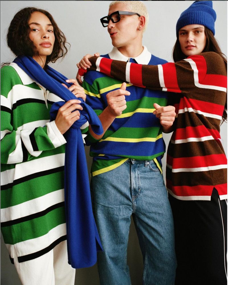 Three fashion models wearing striped shirts and fashionable denim jeans and pants posing in front of a neutral studio backdrop.