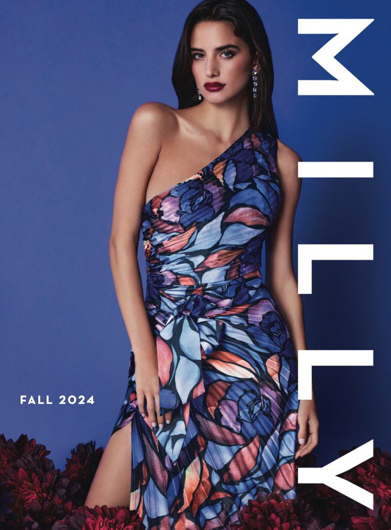 Model in a floral one-shoulder dress posing against a blue background with dark red floral props for Milly Fall 2024.