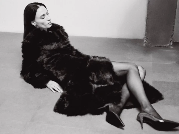 Model in dark fur coat and high heels reclining on a concrete floor for Nour Hammour Resort 25