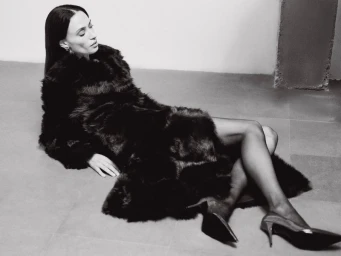Model in dark fur coat and high heels reclining on a concrete floor for Nour Hammour Resort 25