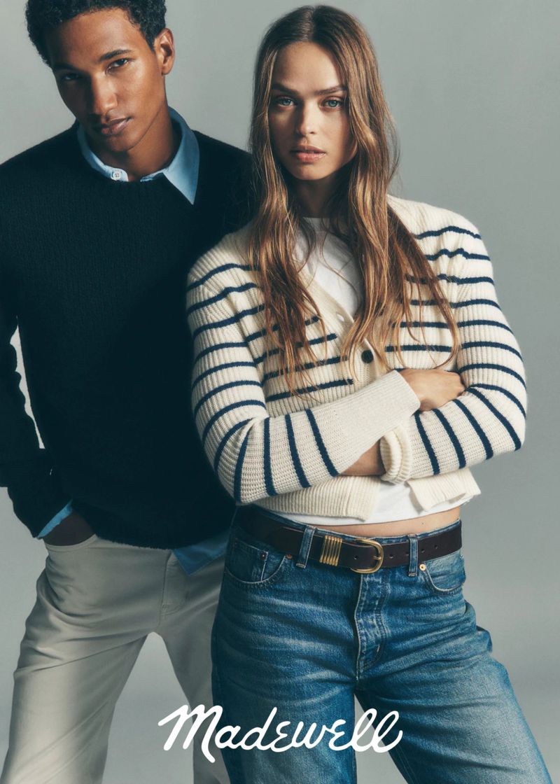 Fashionable couple wearing Madewell clothing, woman in striped cardigan and jeans, man in sweater and pants, studio shot.