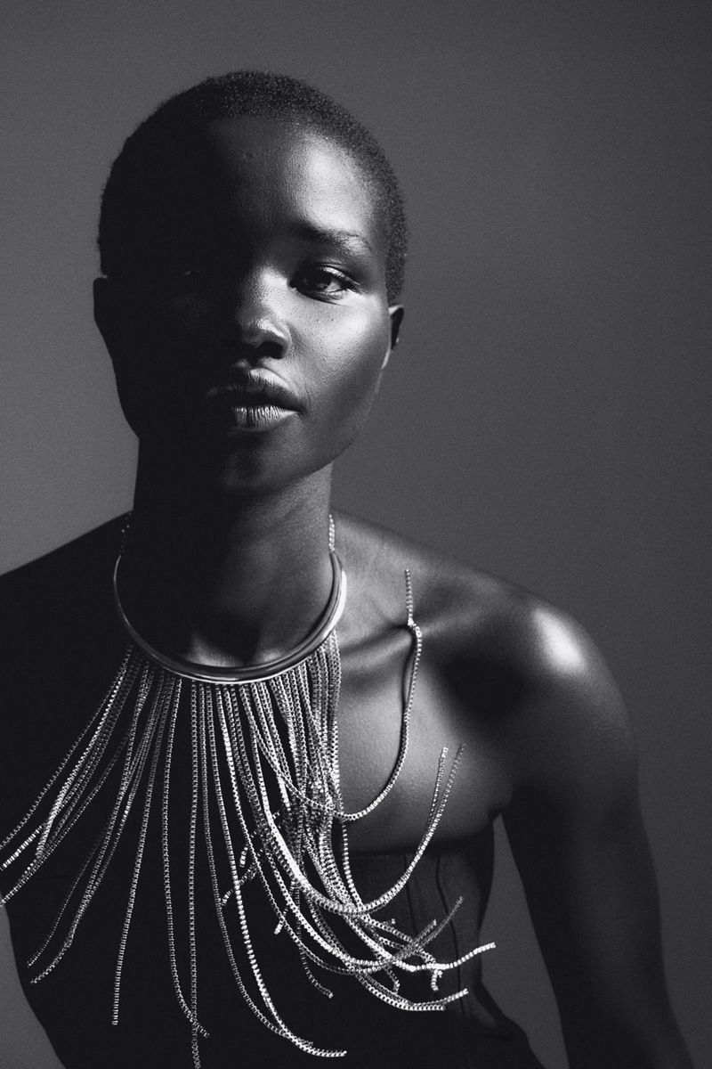 Portrait of a Black woman with short hair wearing a metallic fringe necklace in a studio setting with diffused lighting.