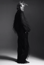 Model in black fringe outfit against dark background for H&M Holiday 2024