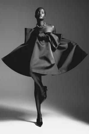 Model in a black strapless flared dress and statement necklace against a grey seamless background
