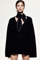Model wearing a black cardigan and studded scarf against a plain white background for H&M lookbook