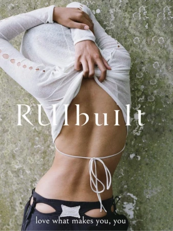 Back view of a slim woman in a white top and black pants against a textured backdrop. Body positivity message 'love what makes you, you'.