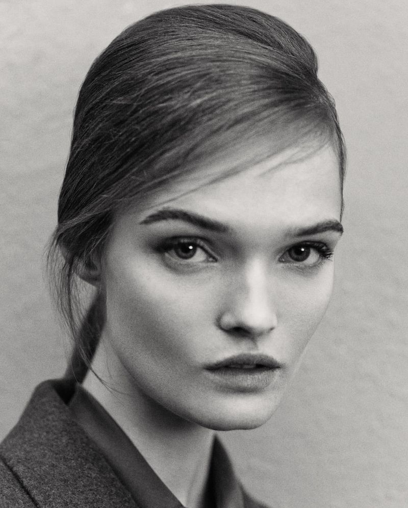 Close up monochrome portrait of model Lulu Tenney with styled hair and dark jacket against plain background