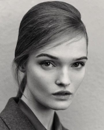 Close up monochrome portrait of model Lulu Tenney with styled hair and dark jacket against plain background
