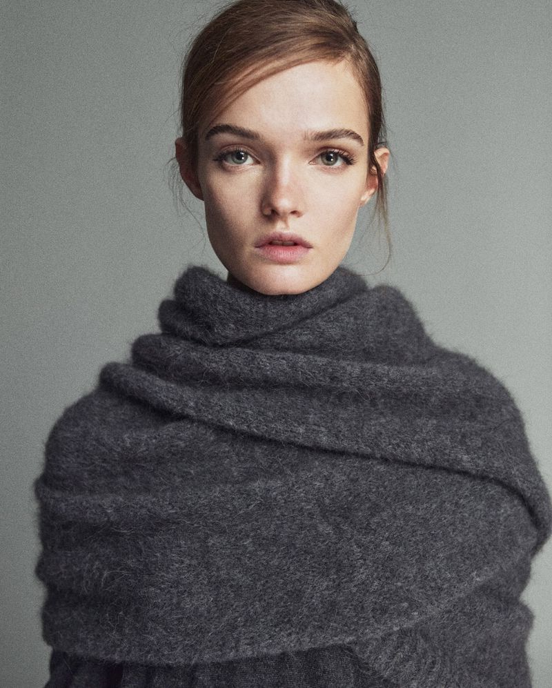 Close-up studio portrait of a fair-skinned adult female model with auburn hair wrapped in a gray wool scarf, looking at the camera.