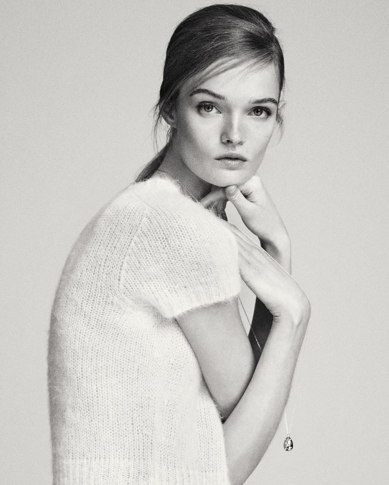 Monochrome portrait of model Lulu Tenney wearing a textured short-sleeve top and a delicate pendant necklace against a light background.