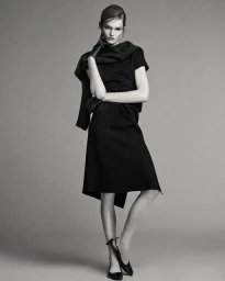 Model Lulu Tenney posing against a grey seamless background for Massimo Dutti L'Allure project, wearing a black dress and leather gloves.