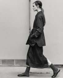 Model Lulu Tenney in a dark coat and skirt walking past a plain wall for Massimo Dutti L'Allure