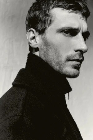 Close-up profile portrait of model Clement Chabernaud wearing a dark high-collared jacket for Zara Man shot by Alvaro Perena Jimenez.