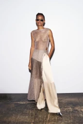Model Ysaunny Brito wearing a sheer metallic knit top and wide silk trousers in a studio setting.