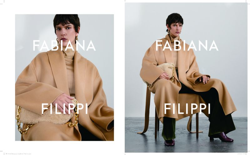 Fabiana Filippi fashion campaign featuring an adult female model in a tan coat and black pants sitting in a photo studio.